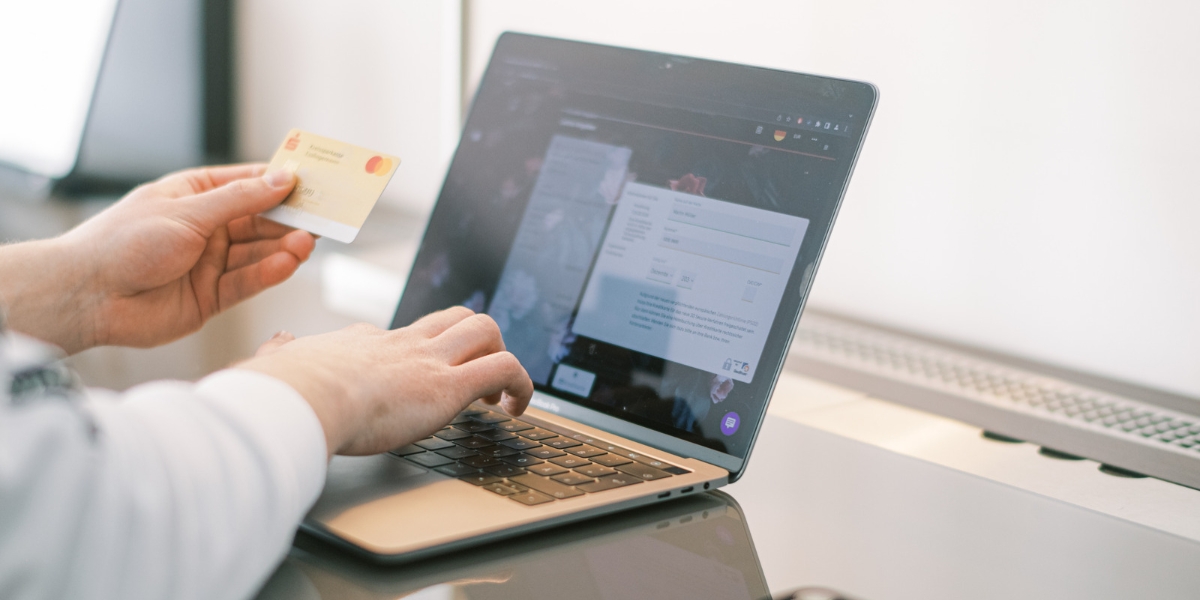 Person gibt an Laptop Kreditkartendaten ein