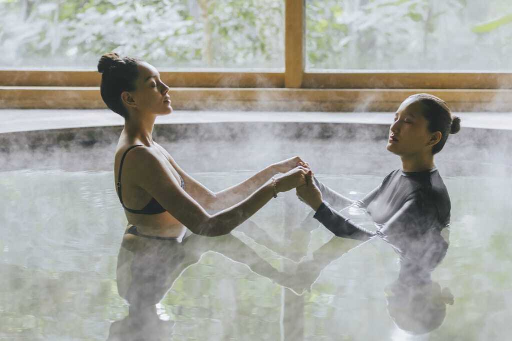 Zwei Frauen genießen die wohltuende Watsu-Therapie, die Körper- und Wassertherapie vereint, um tiefenentspannende Erlebnisse zu schaffen.